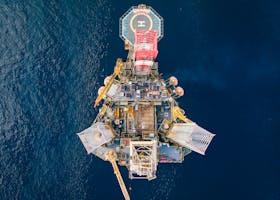 High-angle view of an offshore oil platform with helipad surrounded by deep blue ocean.